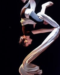 Close-up of woman dancing with fabric against black background