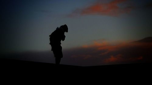 Silhouette man standing against sky during sunset