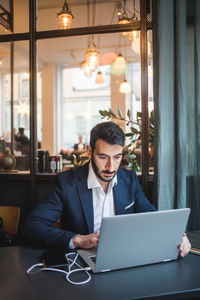 Confident businessman using laptop at desk in creative office