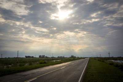 Empty country road against cloudy sky