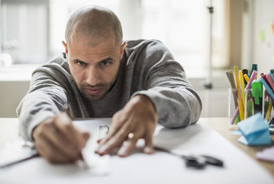 Businessman drawing line on paper at desk in creative office