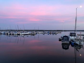 Sailboats moored at harbor against sky during sunset