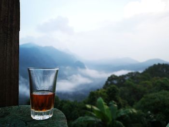 Whiskey glass on table against mountains