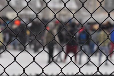 People seen through chainlink fence during winter