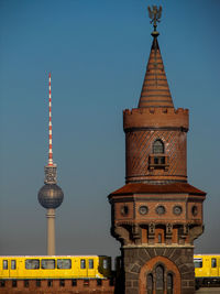 Low angle view of clock tower by fernsehturm against sky
