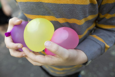 Child wearing striped shirt carefully holds water balloons in hands