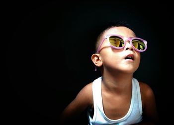 Close-up of cute girl wearing sunglasses against black background