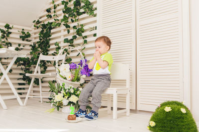 Cute boy with potted plants on floor