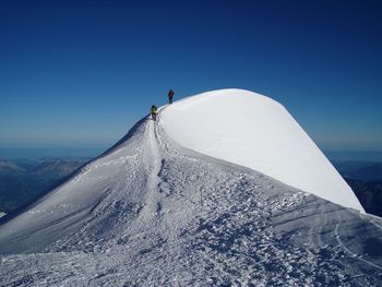 People hiking on snowcapped mountain against sky