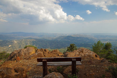 Bench on landscape against sky