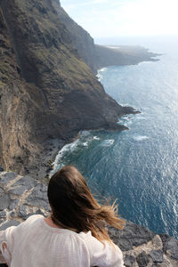 Rear view of woman looking at sea while standing on mountain