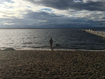 Man standing on beach against sky during sunset