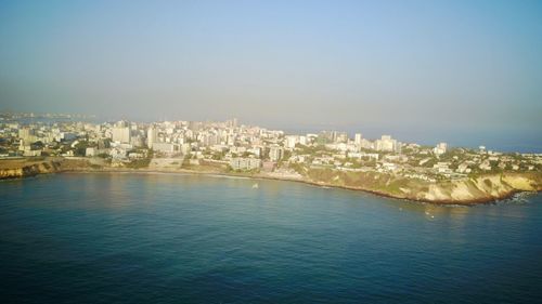 Scenic view of city by sea against clear sky