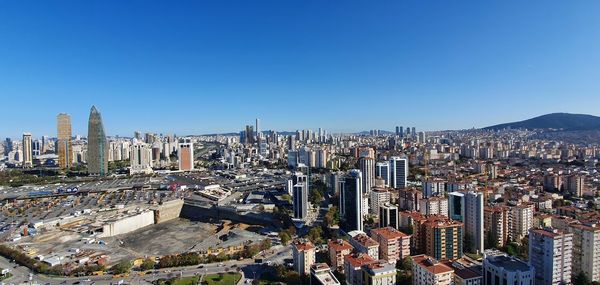 Aerial view of modern buildings in city against clear blue sky