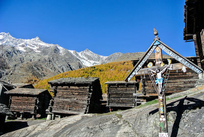 Built structure on snowcapped mountains against clear blue sky