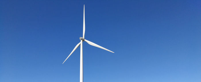 Low angle view of wind turbine against blue sky