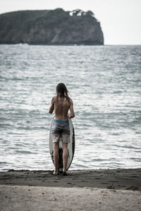 Rear view of shirtless man standing on beach