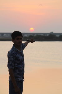 Man standing on beach against sky during sunset