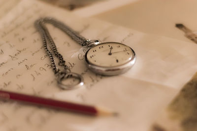 High angle view of pocket watch and pencil on letter