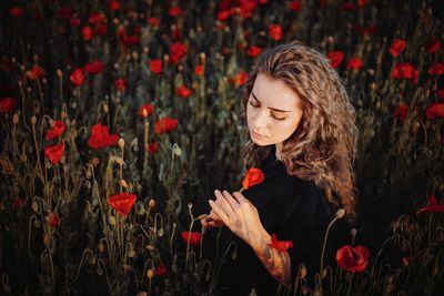 Woman standing by red flowering plants
