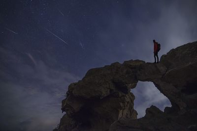 Man standing on rock against sky at night