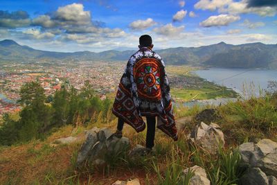 Rear view of man looking at townscape against sky