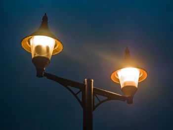 Low angle view of illuminated street light against sky