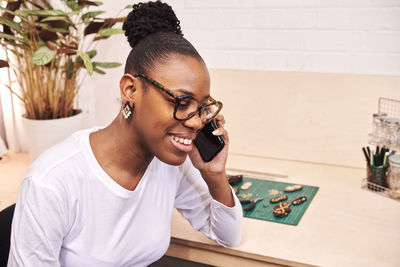 Smiling businesswoman talking on phone while sitting at office