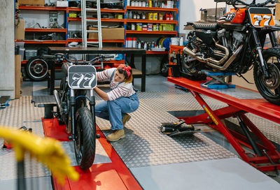 Mechanic woman checking custom motorcycle on factory