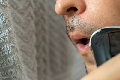 Close-up midsection of man shaving mustache at home