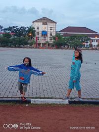 Full length of mother and girl standing against built structure