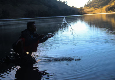 Teenage boy playing with water in lake