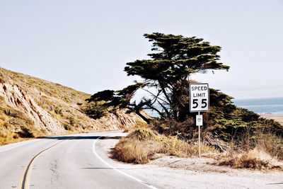 Information sign by road against sky