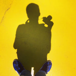 Low section of man standing on yellow shadow