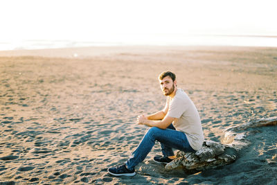 Portrait of young woman sitting on sand at desert