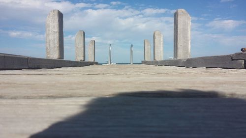 Surface level view of boardwalk against cloudy sky