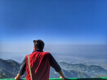 Rear view of man looking at landscape against sky