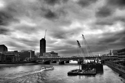 Bridge over river against cloudy sky