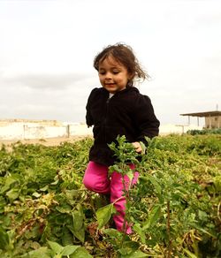 Girl amidst plants on field against sky