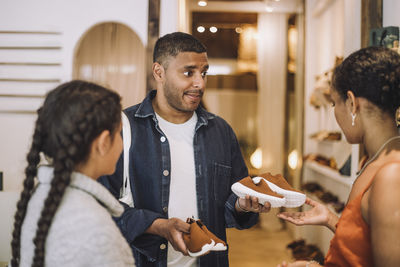 Man holding shoes by daughter talking with saleswoman at boutique