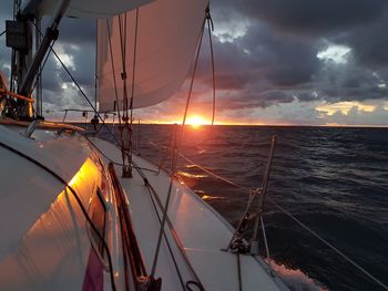 Sailboat sailing on sea against sky during sunset