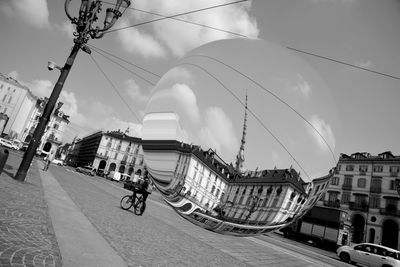 People riding bicycle on city street against sky