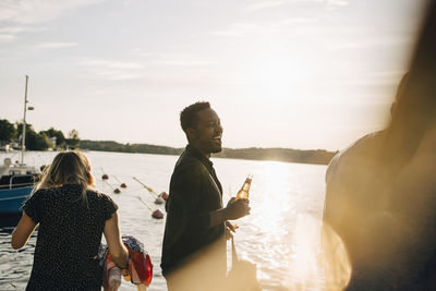 People sitting on shore against sky