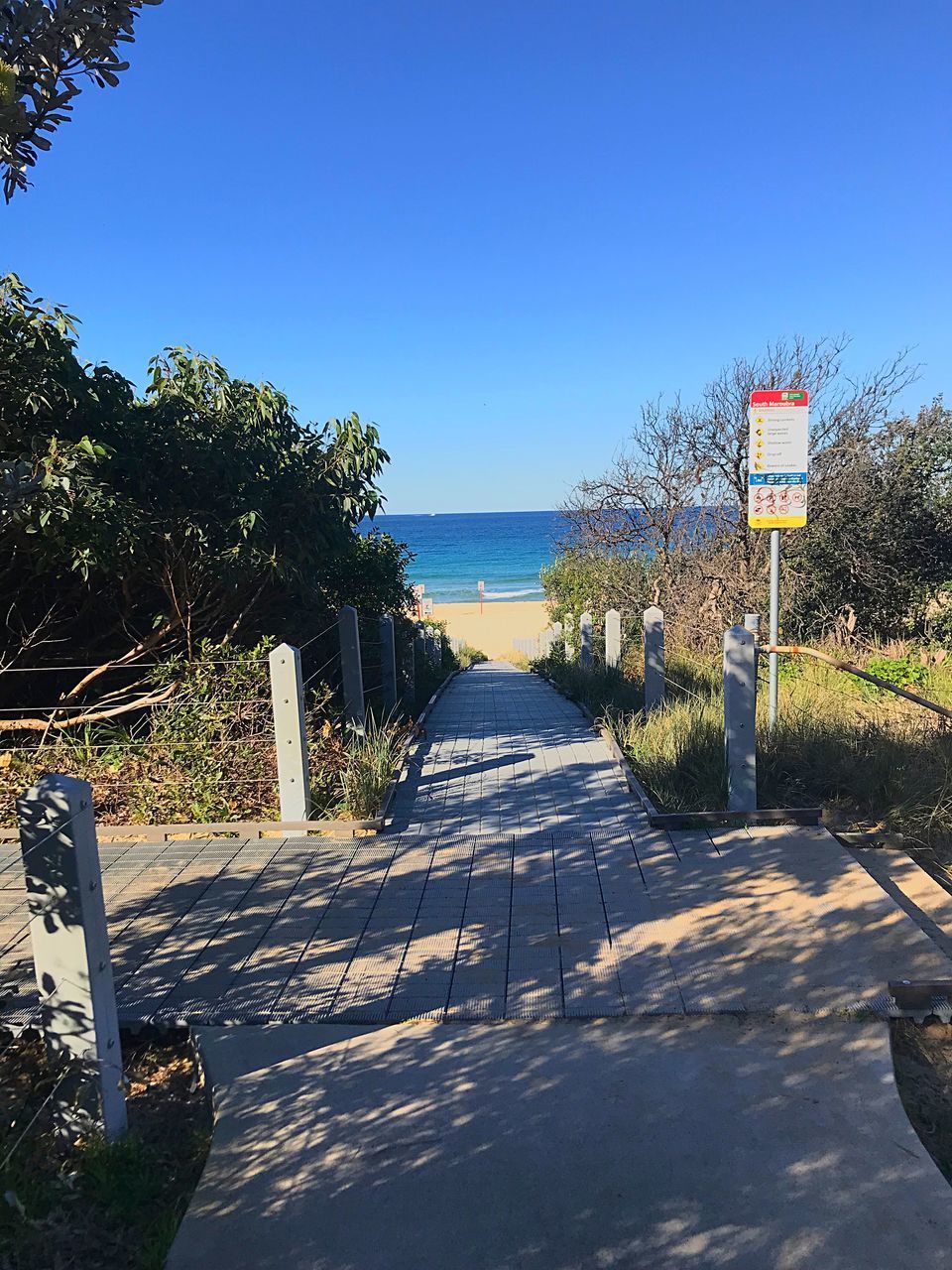 VIEW OF ROAD BY SEA AGAINST CLEAR SKY