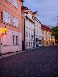 Street amidst buildings in city at dusk