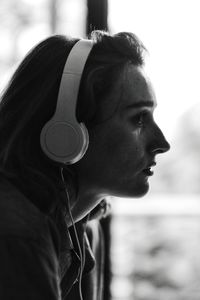 Profile view of thoughtful woman crying while listening to music through headphones