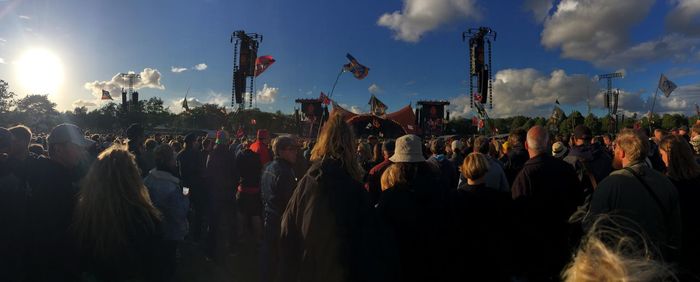 Panoramic view of crowd at music concert against sunny sky