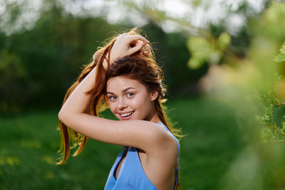 Portrait of young woman standing against plants