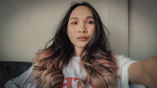 Portrait of young woman against wall at home