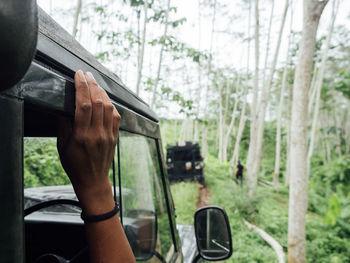 Cropped hand of person sitting in off-road vehicle in forest